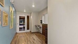 A hallway with wooden flooring, a door leading to a room, and a small kitchenette area with a sink and a coffee machine. - WoodSpring Suites Macon North I-75 (Macon)
