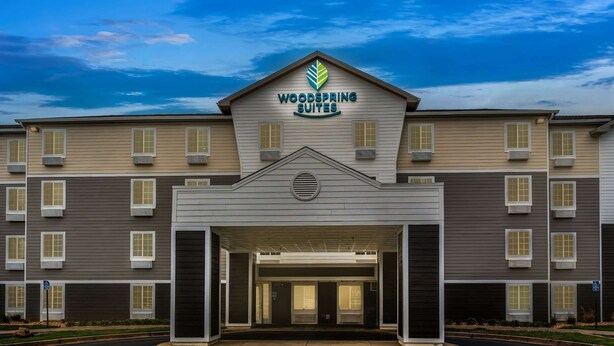 A multi-story hotel with a central entrance, marked by a sign reading "Woodspring Suites." - WoodSpring Suites Macon North I-75 (Macon)