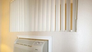 A room with a white radiator, a window with vertical blinds, and a plain wall. - Sunset Inn and Suites (West Sacramento)