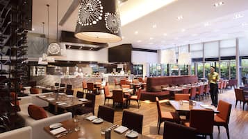Un restaurante espacioso con varias zonas de comedor, incluyendo un bar y un área con vistas al exterior.