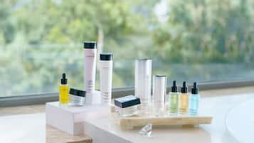 A display of skincare products on a marble countertop with a view of trees through a window.