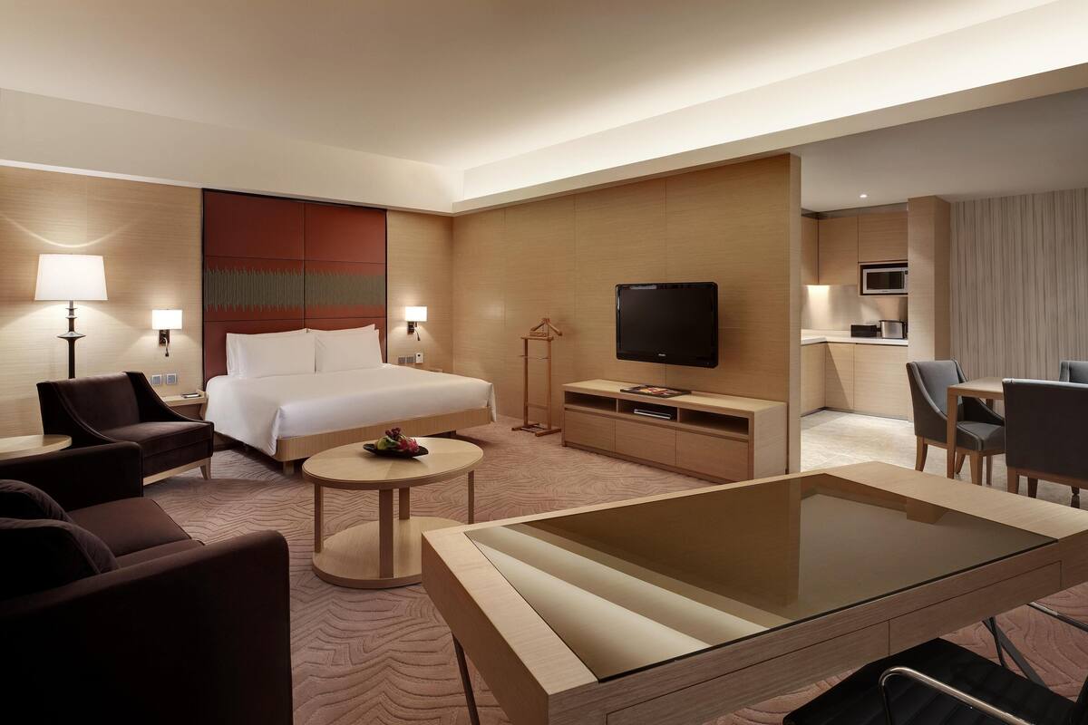 A hotel room with a bed, a TV, a desk, a chair, and a sofa.