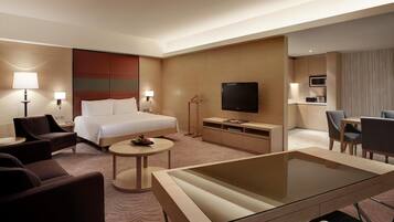 A hotel room with a bed, a TV, a desk, a chair, and a sofa.