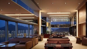 A spacious lounge area with multiple seating options, a dining area, and large windows offering city views.