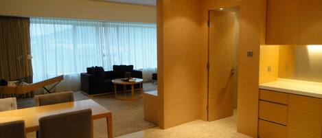 A modern hotel room with a dining area, a sofa, and a kitchen.