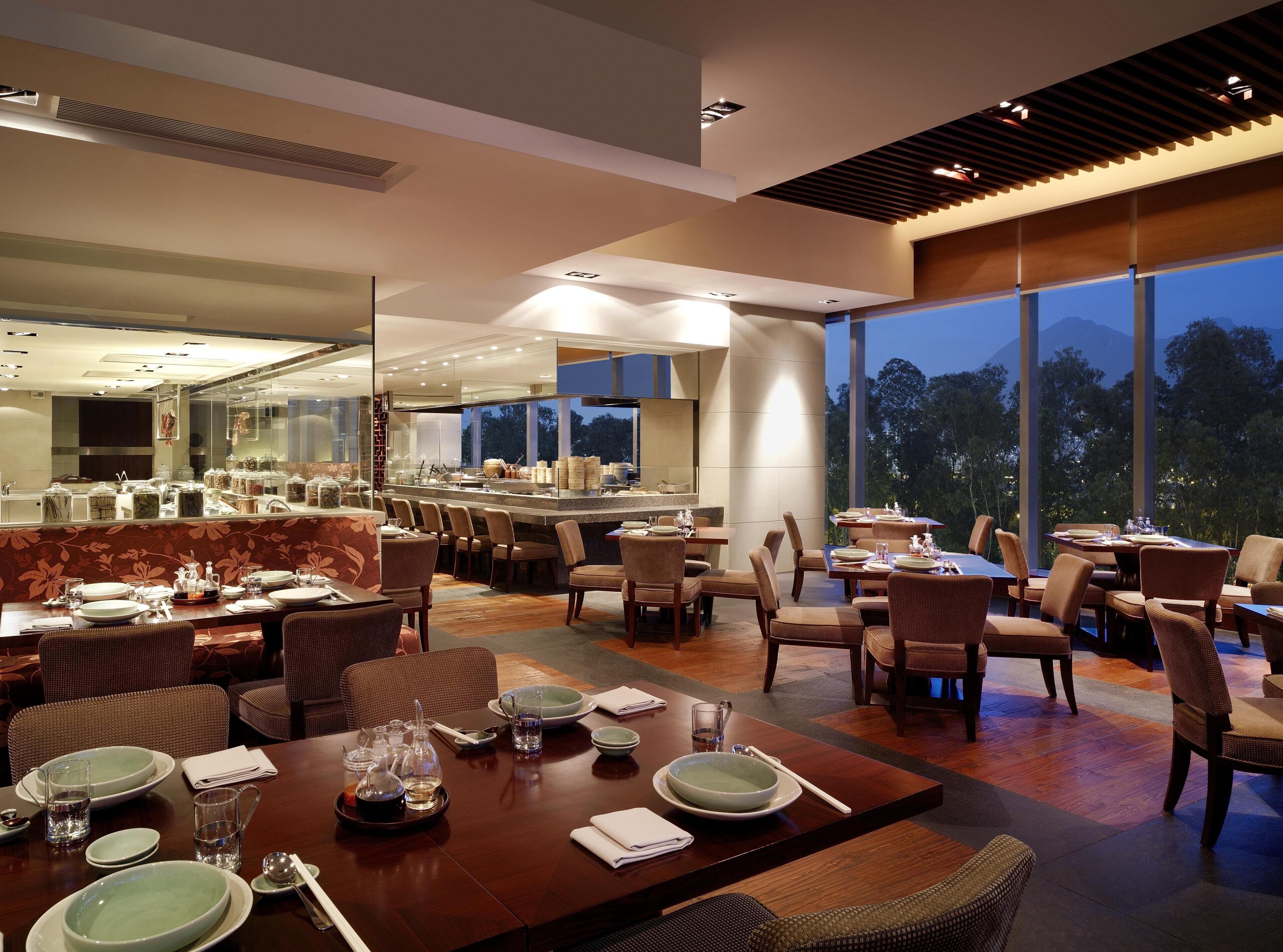 Un comedor moderno con varias mesas, sillas y vistas al exterior.