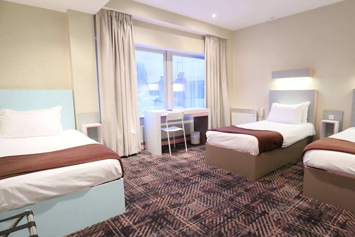 A hotel room with two beds, a desk, and a chair.