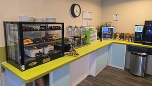 A bakery counter with various baked goods, a coffee machine, and a clock on the wall. - Citrus Hotel Cheltenham by Compass Hospitality (Cheltenham)