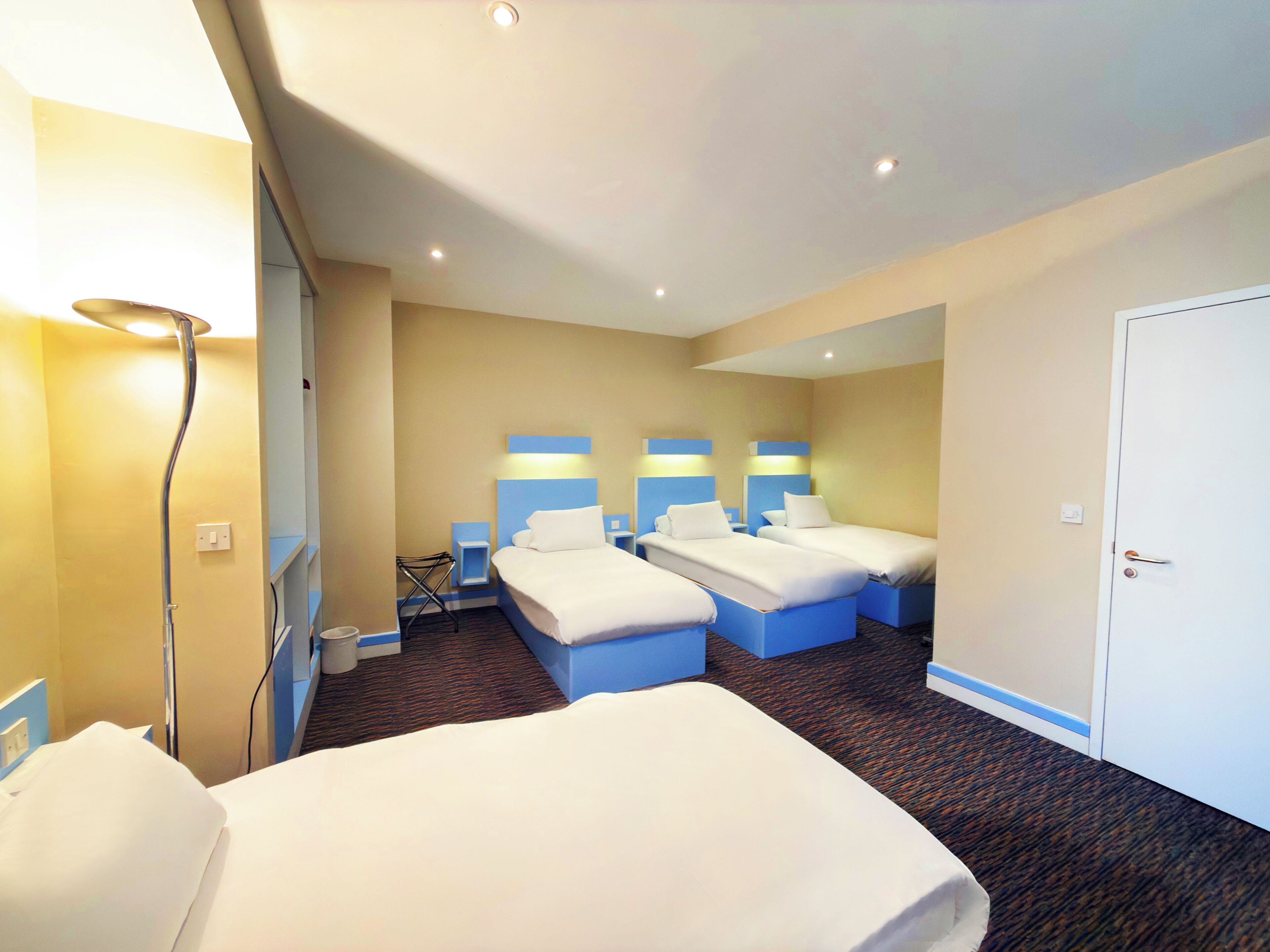Una habitación de hotel con tres camas, ducha y puerta.