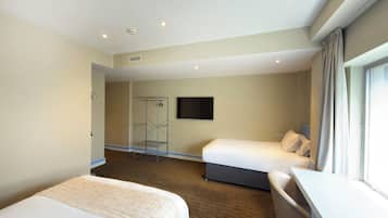 A hotel room with two beds, a desk, a shower area, and a TV.