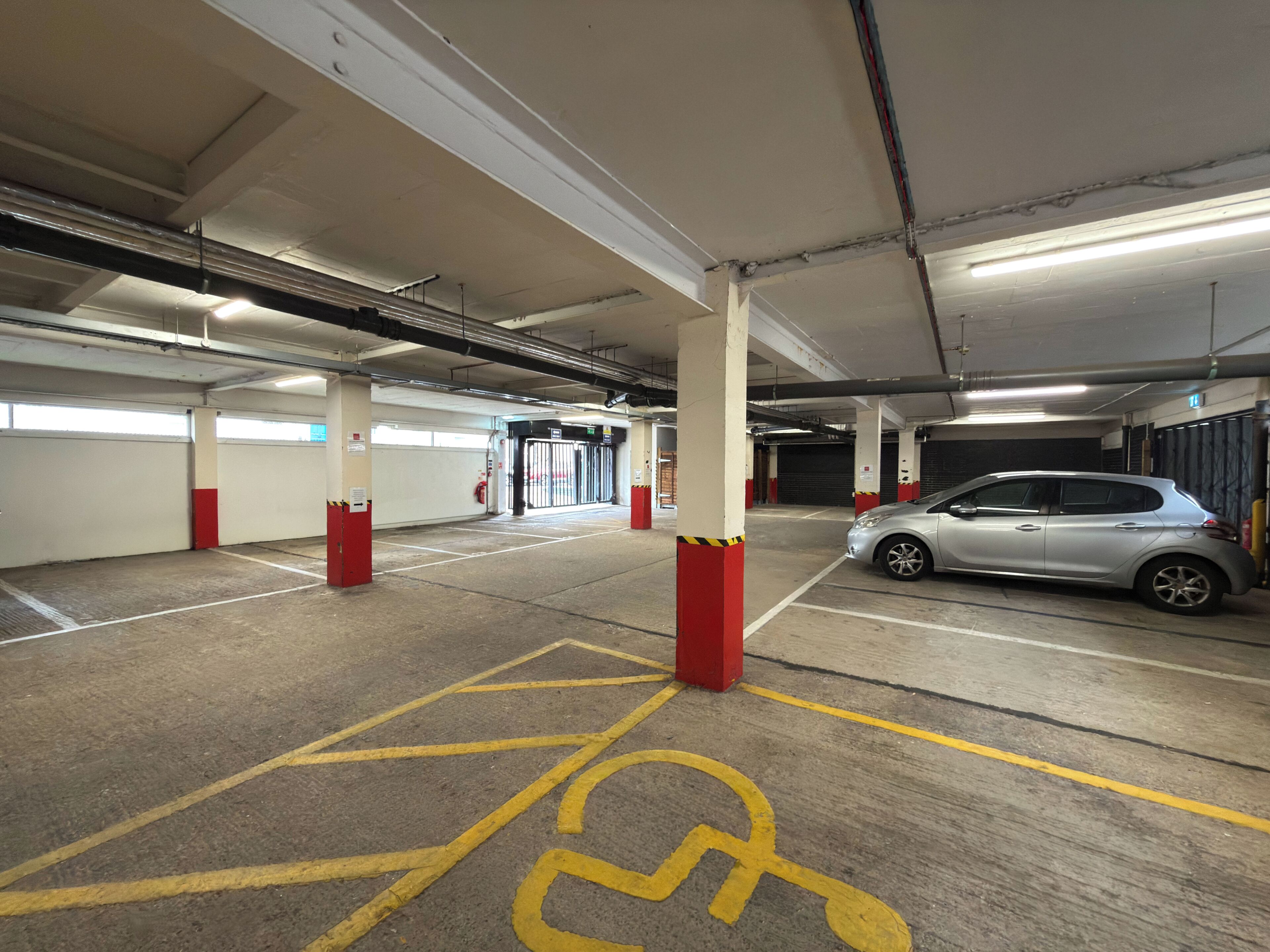 A multi-level parking garage with concrete pillars, marked parking spaces, and a fire extinguisher.