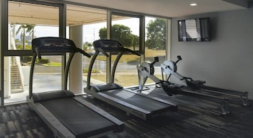 Un gimnasio con cintas de correr, una bicicleta estática y una máquina de remo.