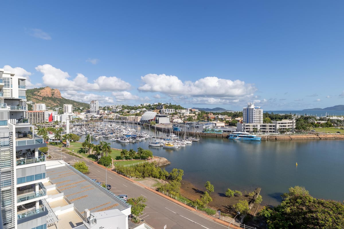 A marina with boats, a road, and modern buildings.