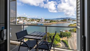 Balcón con mesa y sillas que da a un puerto deportivo con barcos y vistas de la ciudad.