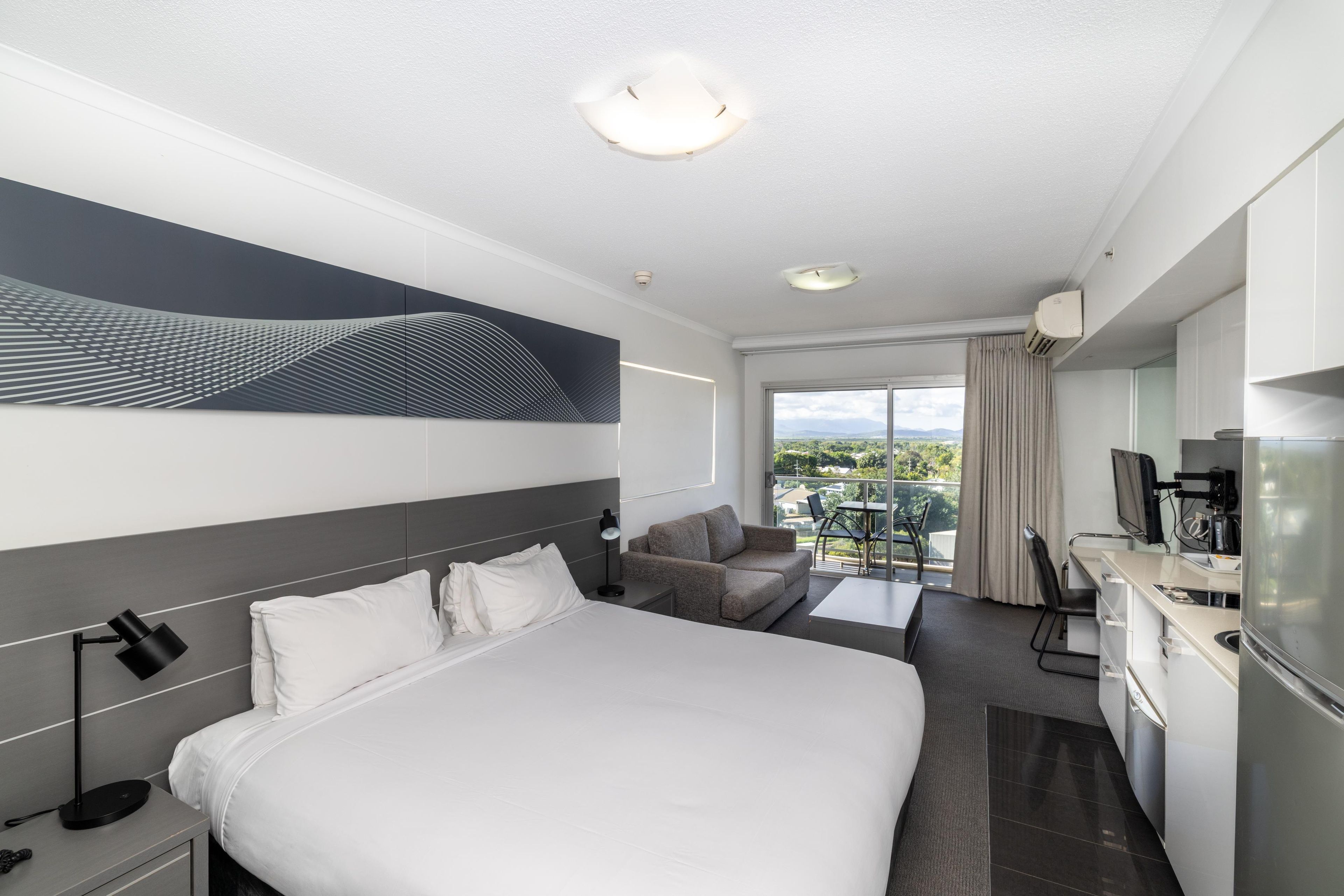 Une chambre d’hôtel avec un lit, un bureau, un canapé et un balcon offrant une vue.