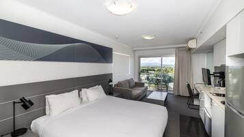 A hotel room with a bed, a desk, a sofa, and a balcony with a view.