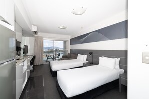 Une chambre d’hôtel avec deux lits, un bureau, une chaise et une vue sur la ville.