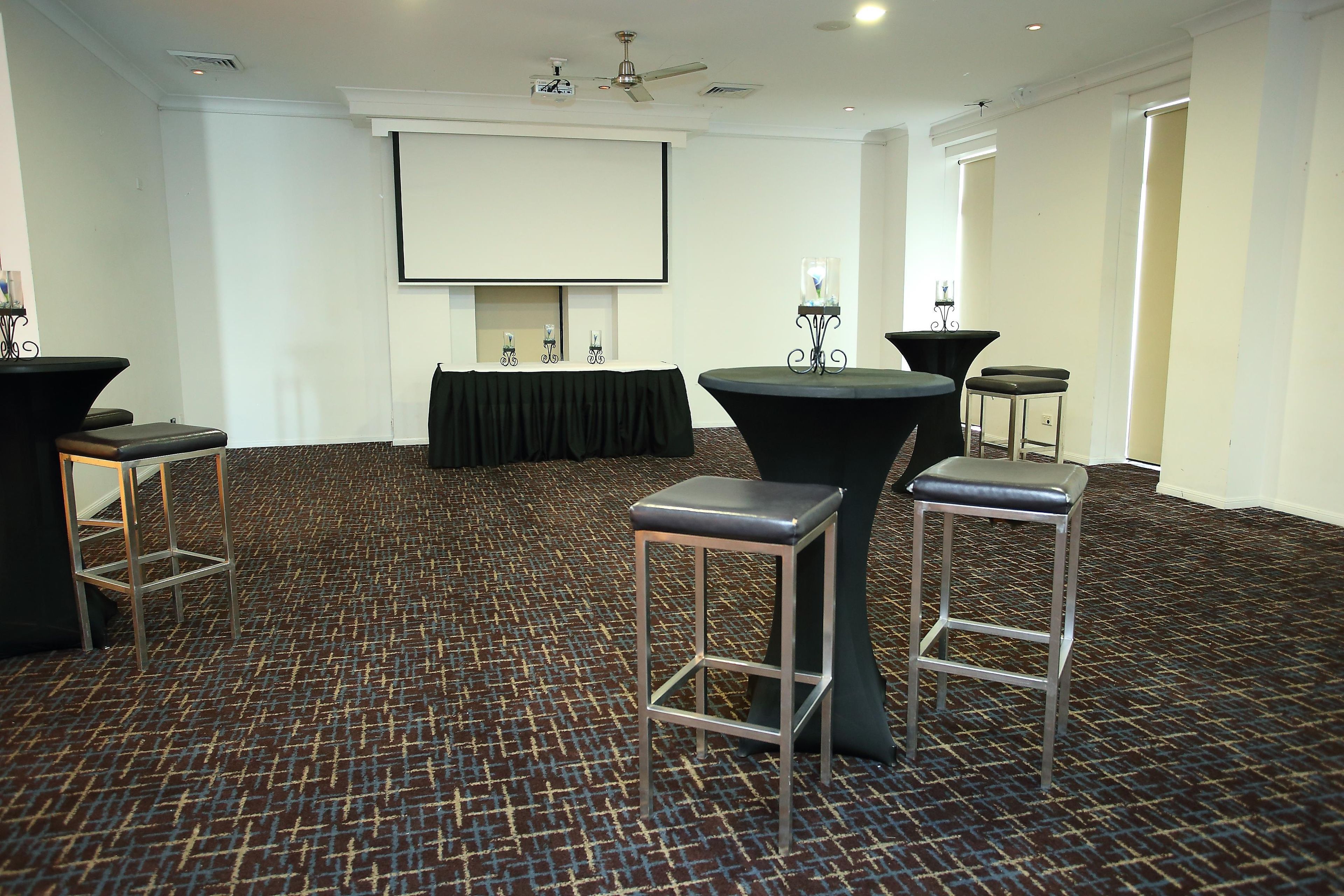 Une salle de conférence équipée d’un grand écran, de tables et de chaises.