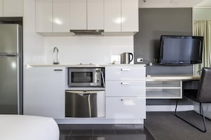 Una cocina moderna con microondas, hervidor y televisor de pantalla plana.