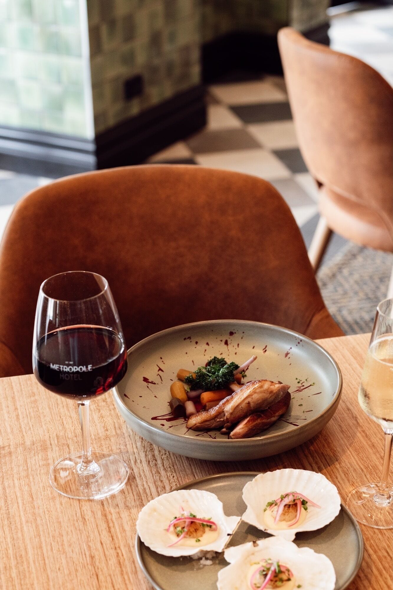 A dining table with a plate of food, a glass of red wine, and a glass of white wine.