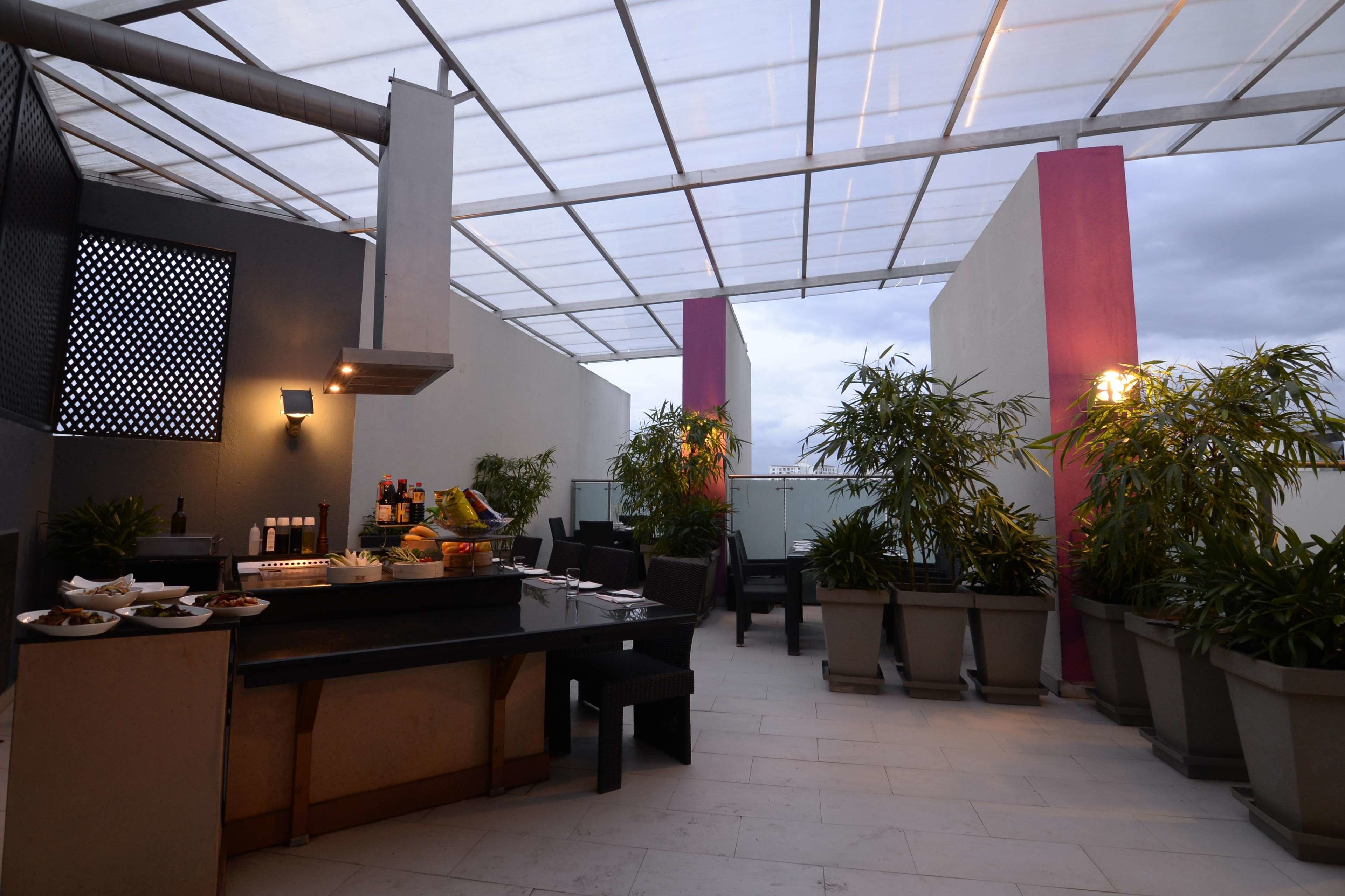An outdoor patio area with a bar, seating, and potted plants.