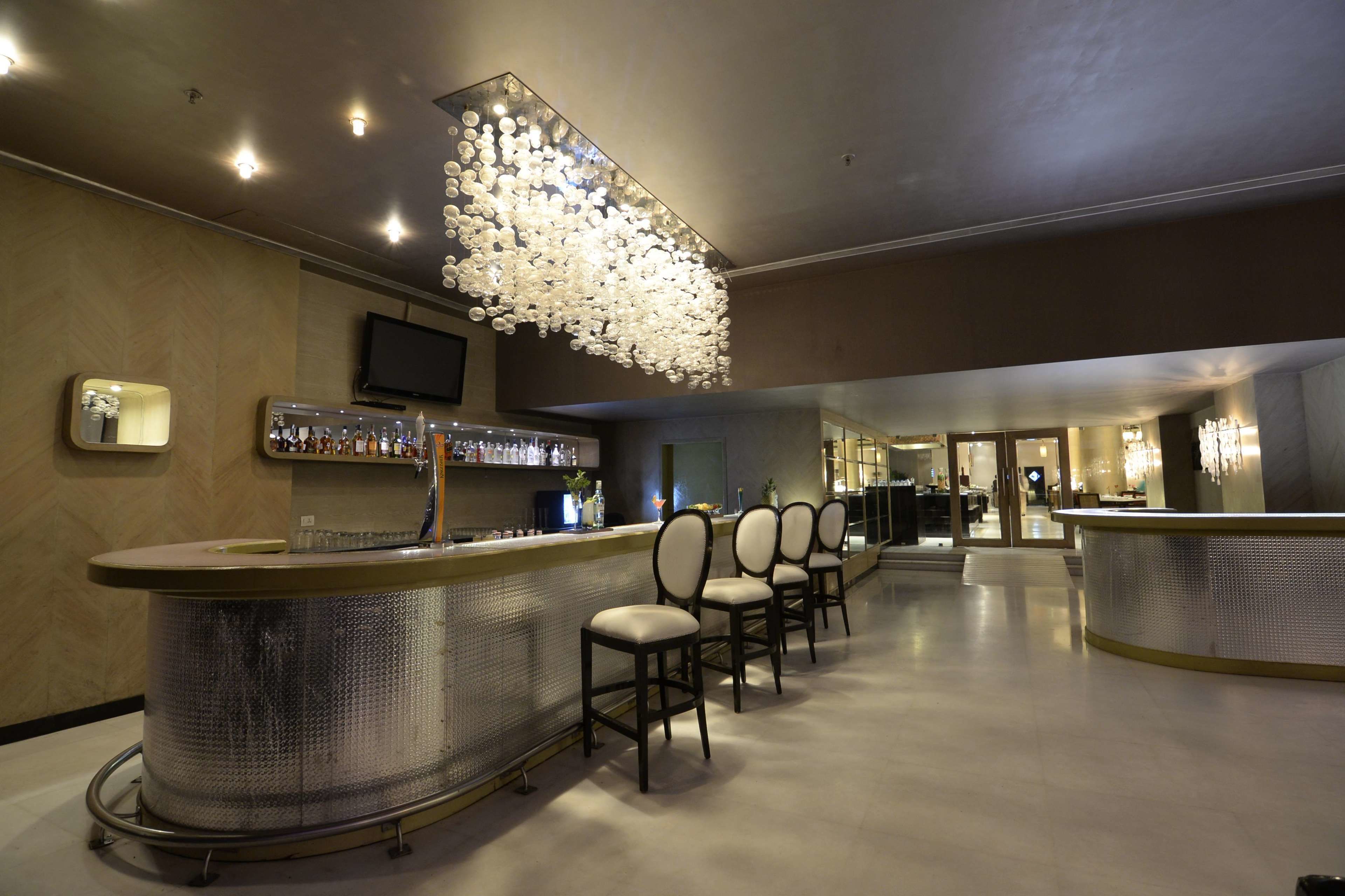 Una zona de bar con mostrador curvo, varias sillas y una lámpara decorativa.