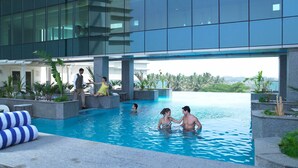 A modern indoor pool area with clear blue water, surrounded by stone pillars and tropical plants. - The Zuri Whitefield, Bangalore (Bengaluru)