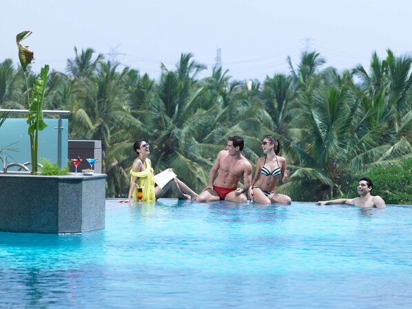 Zona de piscina con palmeras al fondo.