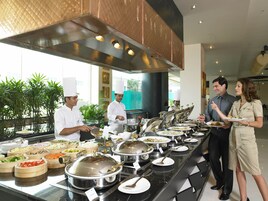 A buffet setup with various food stations, chefs serving, and guests dining.