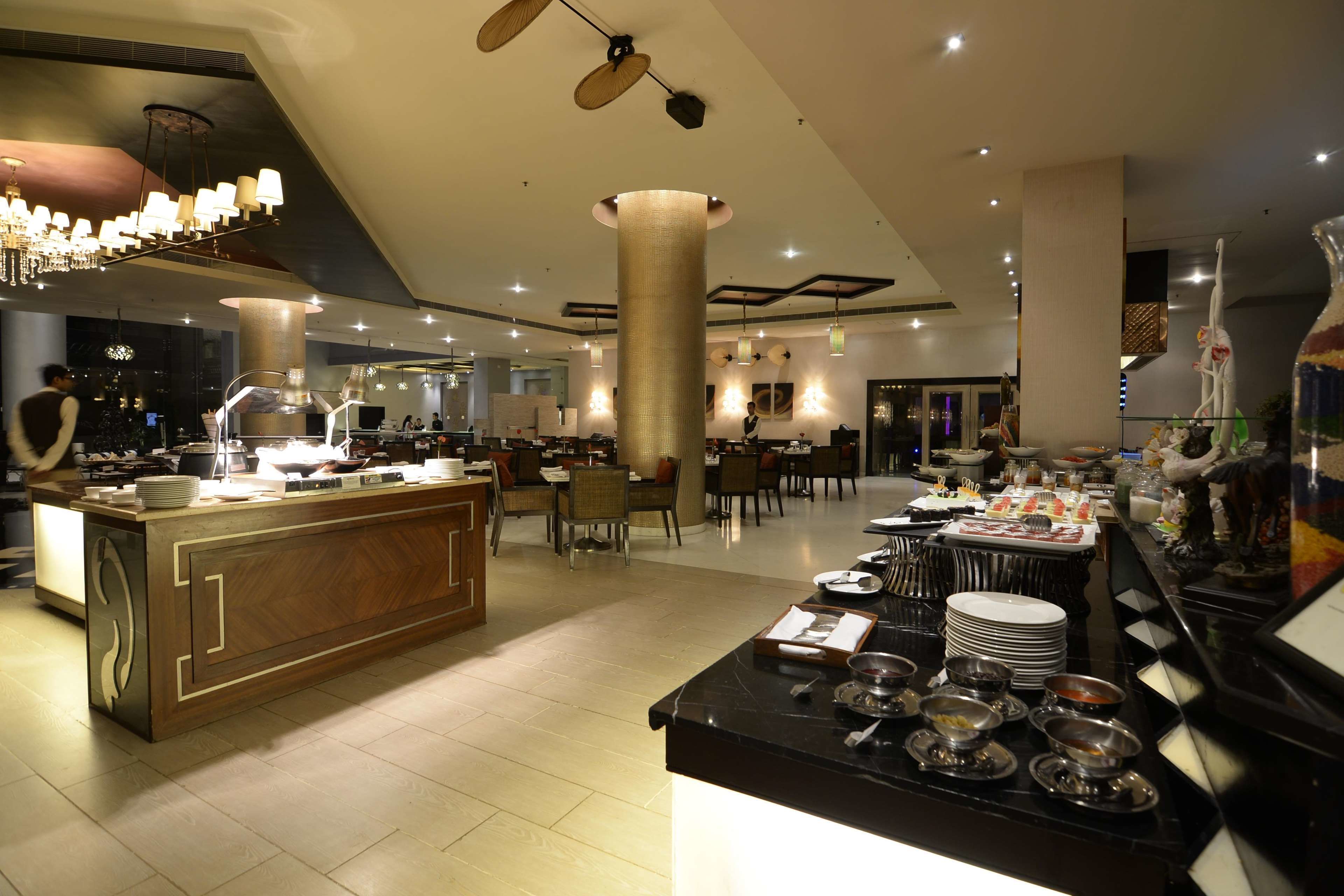 Eine moderne Hotelhalle mit einer zentralen Bar, Esstischen und einem Buffetangebot.