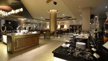 Eine moderne Hotelhalle mit einer zentralen Bar, Esstischen und einem Buffetangebot.