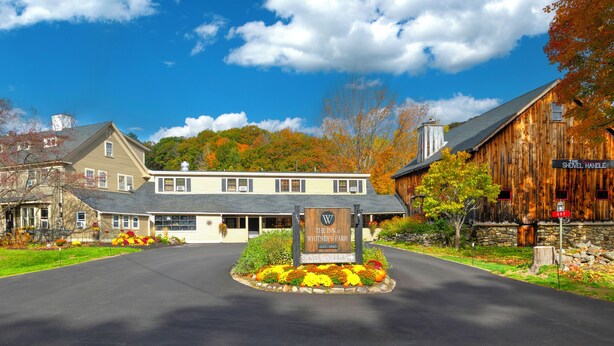 A quaint inn with a welcoming entrance, a shovelful handle pub sign, and a stone wall.
