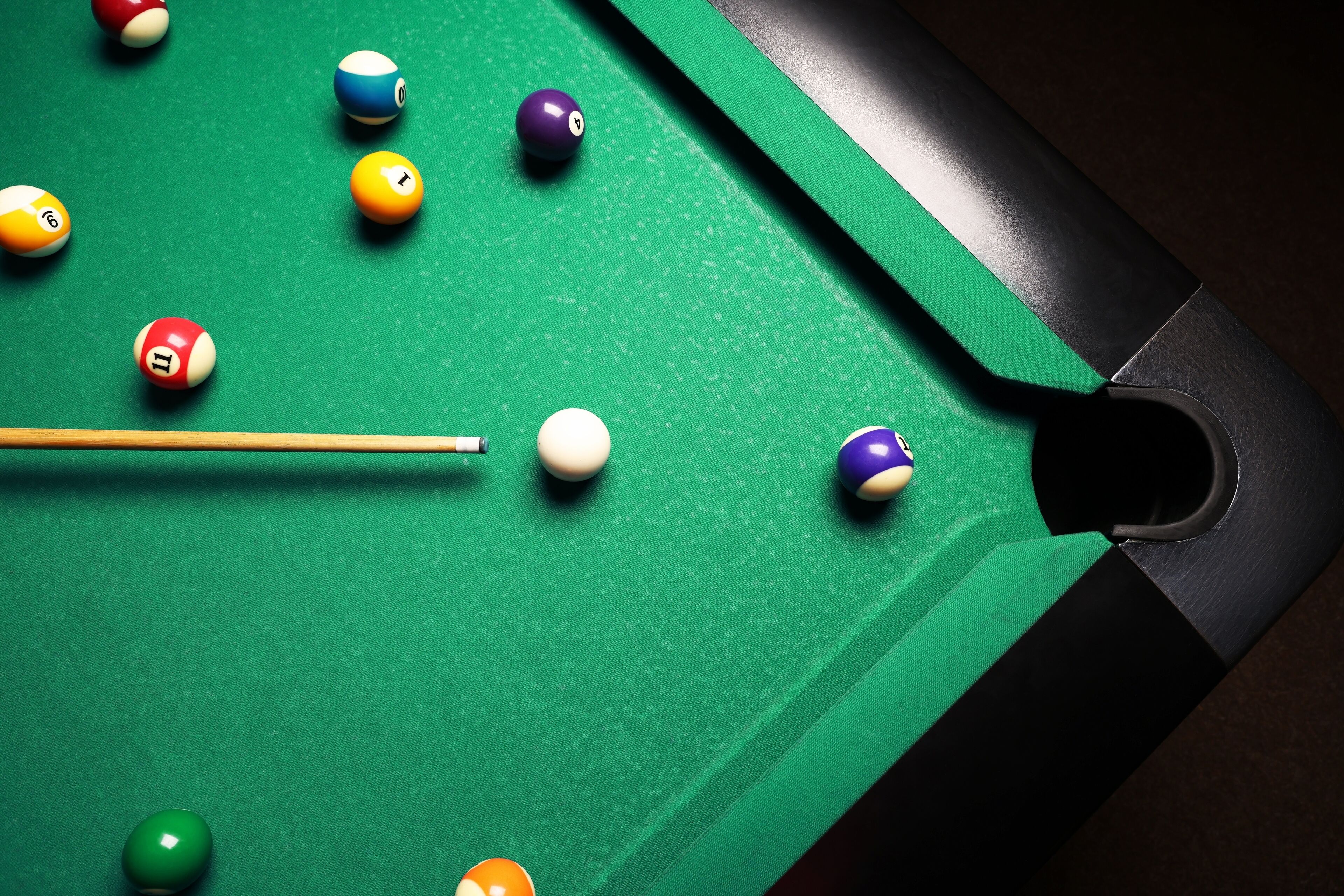 A pool table with various colored balls and a cue stick.