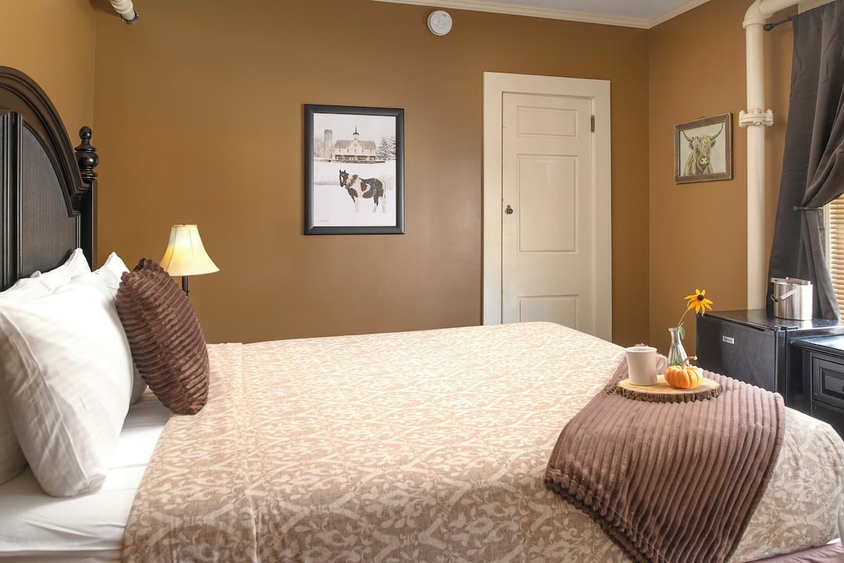 A neatly made bed with a patterned bedspread, a lamp, and a framed picture on the wall.