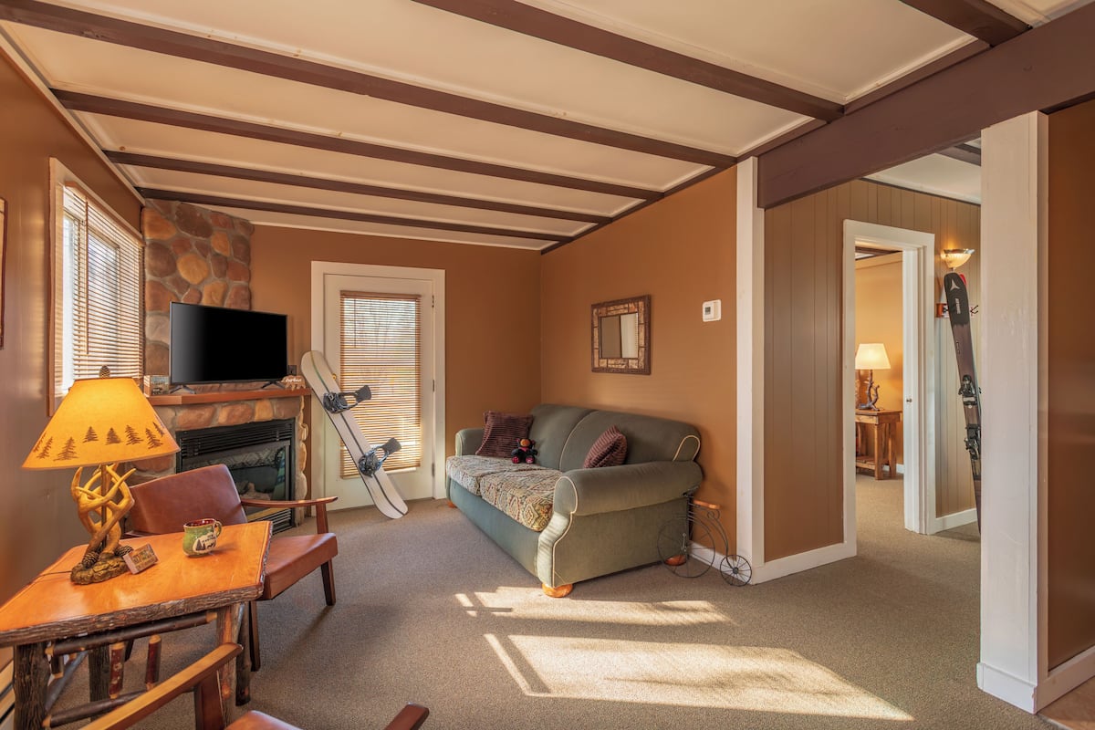 A cozy living room with a stone fireplace, a television, and a sofa.