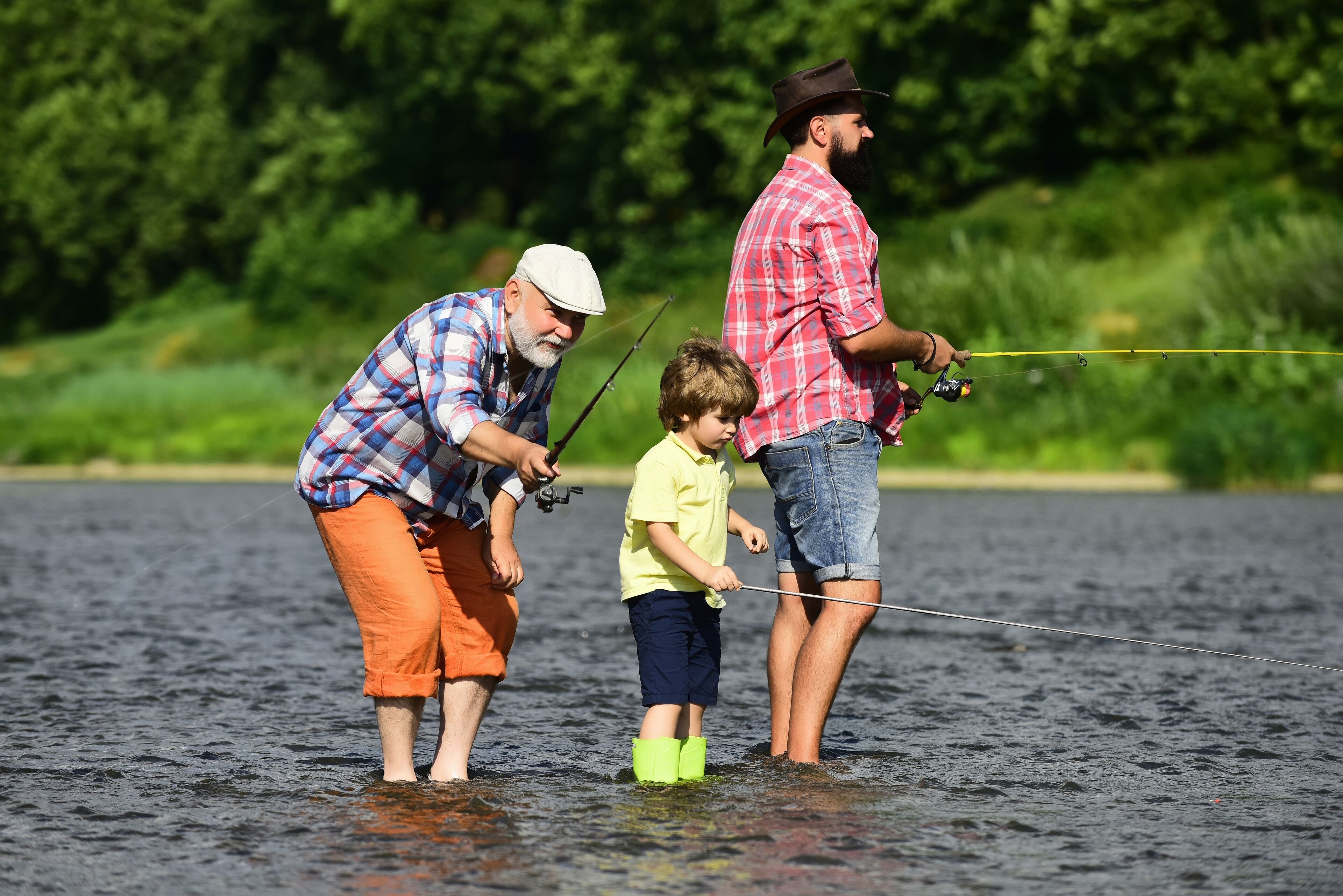 Trois personnes sont en train de pêcher au bord d’une étendue d’eau calme.
