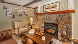 A cozy living room with a stone fireplace, a comfortable sofa, and a wooden coffee table. - Whitneys Inn at Black Mountain (Jackson)