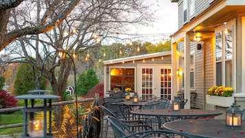 An outdoor patio with tables and chairs, string lights, and lanterns.
