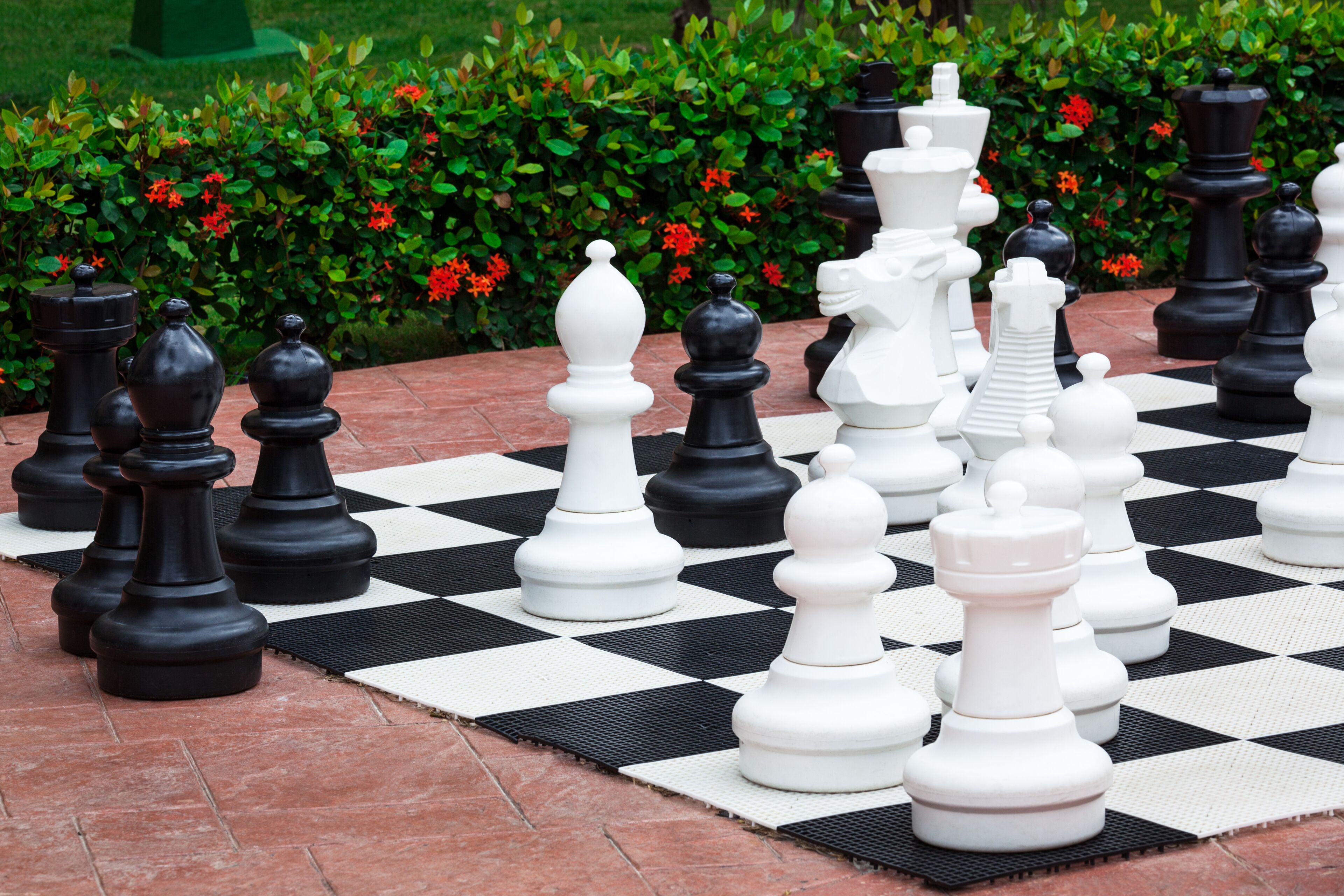 A large outdoor chessboard with chess pieces arranged for a game.
