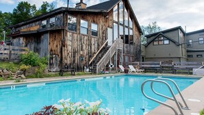 A rustic wooden building with a pool and lounge chairs. - Whitneys Inn at Black Mountain (Jackson)