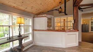 A kitchen with a wooden ceiling, a sign reading "MOUNTAIN TOP", and a window with a lamp on a table.