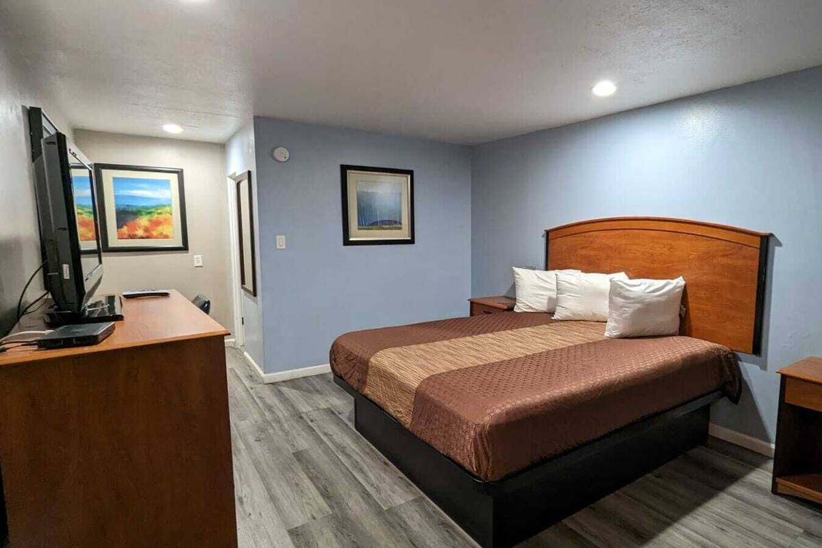 A hotel room with a bed, a desk, and a nightstand.