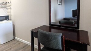 A small room with a wooden desk, a chair, a microwave, and a large mirror. - Best Motel (Barstow)