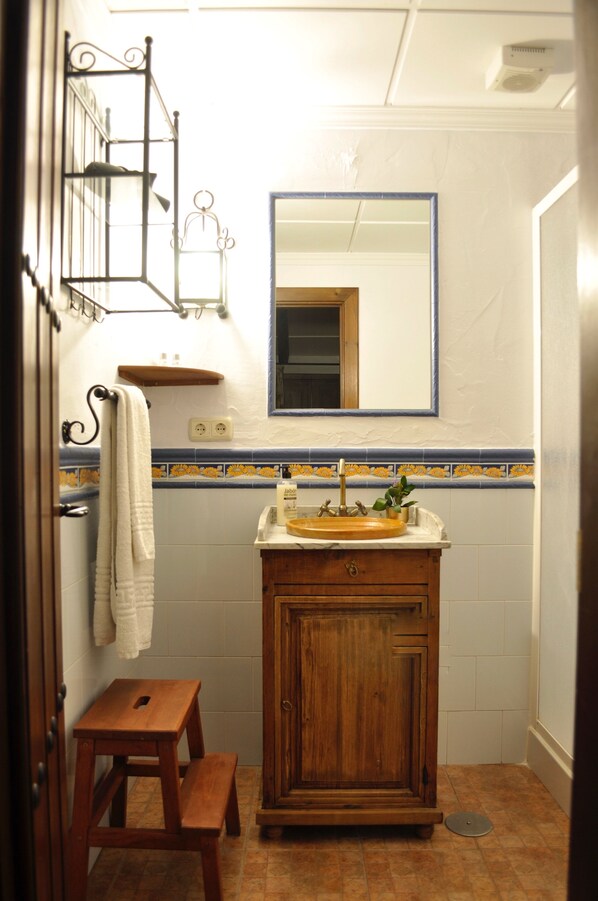 Un baño con un armario de madera, un lavabo con un espejo encima y una toalla colgada en la pared.