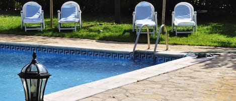 Piscina com espreguiçadeiras e um poste de luz.
