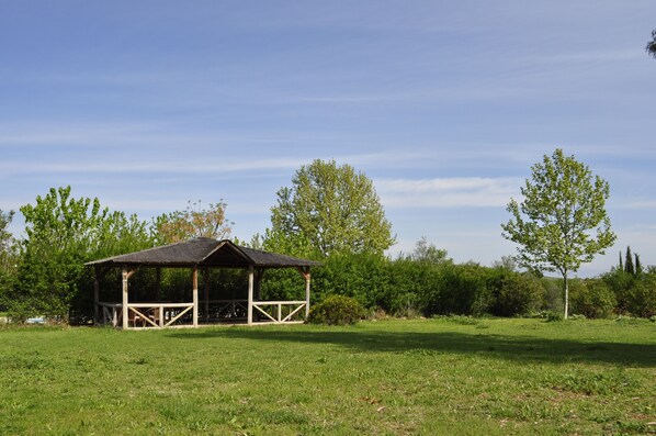 A wooden pavilion in a grassy field with trees in the background. - Rural La Paloma (Villanueva de Tapia)