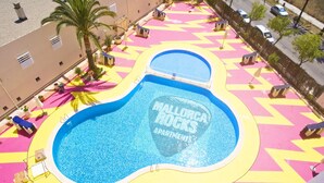 A swimming pool with a guitar-shaped design, surrounded by colorful tiles and palm trees. - Mallorca Rocks Apartments (Calvia)