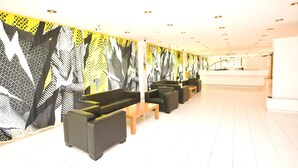 A modern hotel lobby with a long reception desk, multiple seating areas, and a patterned wall design. - Mallorca Rocks Apartments (Calvia)