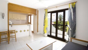 A bright kitchen with wooden cabinets, a small table, and a ceiling fan. - Mallorca Rocks Apartments (Calvia)