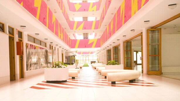 A modern hotel lobby with a central seating area, glass doors, and a striped floor. - Mallorca Rocks Apartments (Calvia)
